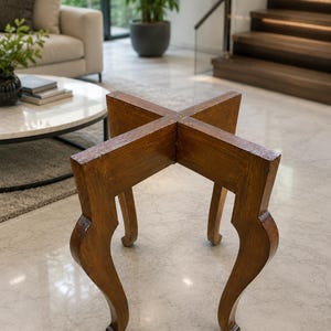 May include: A small, wooden side table with a cross-shaped top and four curved legs. The table is made of a warm-toned wood and has a glossy finish. The legs are elegantly curved, adding a touch of classic design to the piece.