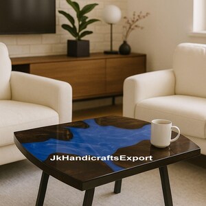 May include: A square coffee table with a dark wood border and a blue resin center. The table has black legs and a white mug on top. The text "JkHandicraftsExport" is visible on the table.