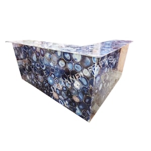 May include: A blue agate stone bar with a clear, glossy finish. The bar has a unique, natural pattern of blue and white circular designs. The bar is L-shaped and appears to be made of stone.