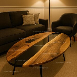 May include: Oval coffee table with a dark wood grain finish and black resin inlay. The table has a black metal frame and legs. The room features a dark sofa, armchair, and a floor lamp.