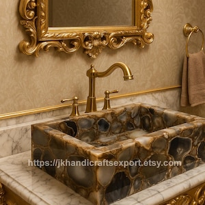 Puede incluir: Un lavabo rectangular de piedra con un patrón de mosaico en tonos grises, marrones y crema. Cuenta con un grifo dorado y está colocado sobre una encimera de mármol. Un espejo con marco dorado está encima. La URL de la tienda Etsy es visible.