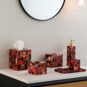 May include: Bathroom accessories set with a unique pattern of red, orange, and brown circles. The set includes a tissue box, soap dispenser, tray, and other matching items. The items are displayed on a white countertop.