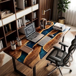 Puede incluir: Un escritorio rectangular con una losa de madera de borde natural y una incrustación central de resina azul, sostenido por patas de metal negro. La superficie del escritorio contiene una computadora portátil, teclado, ratón, dos portalápices y un cuaderno.