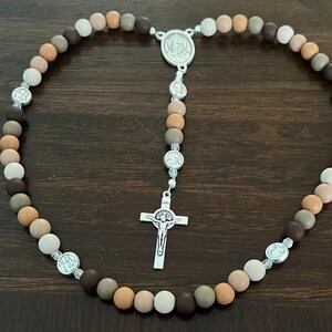 May include: A brown, beige and white wooden bead rosary with a silver crucifix and silver medallions.