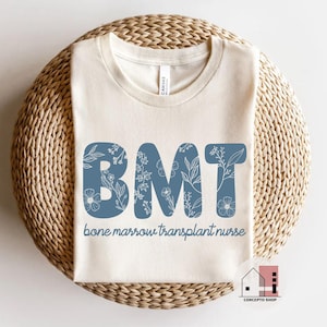 May include: A white t-shirt with a blue floral design that spells out "BMT" and the text "bone marrow transplant nurse".