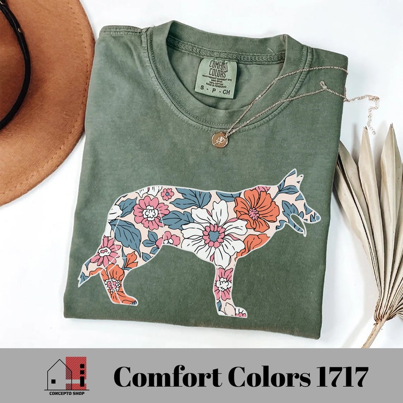 Pu&ograve; includere: Una maglietta verde con una silhouette di pastore tedesco con stampa floreale. La maglietta ha un'etichetta che dice "Comfort Colors" e "S - P - CH".