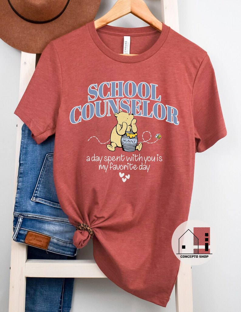 May include: A red t-shirt with the text "SCHOOL COUNSELOR" in blue letters. A cartoon bear with a honey pot is pictured below the text. The text "a day spent with you is my favorite day" is below the bear.