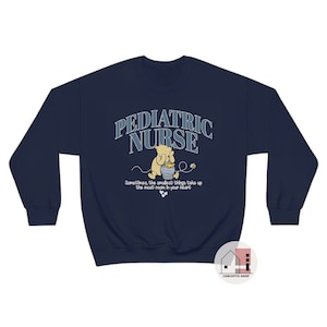 May include: Navy blue sweatshirt with a Winnie the Pooh illustration and the text "Pediatric Nurse" in a blue and white arched font. The text below the illustration reads "Sometimes, the smallest things take up the most room in your heart."