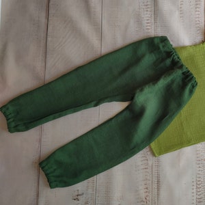 May include: A pair of dark green linen pants with a drawstring waist and elastic cuffs.