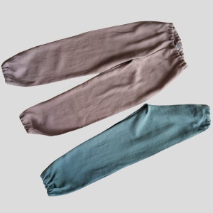 Op de afbeelding: Twee broeken, een in lichtbruin en de andere in donkerblauw. Beide broeken hebben een trekkoord in de tailleband en een ontspannen pasvorm.