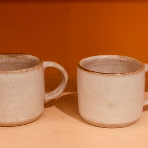 A pair of Handmade ceramic espresso coffee mugs in cream or biscuit coloured glazes
