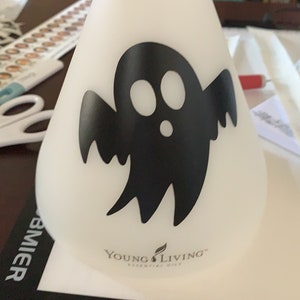 May include: White ceramic diffuser with a black ghost design and the text "Young Living Essential Oils".