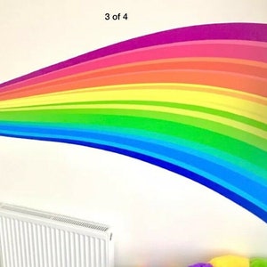 Puede incluir: Una calcomanía de pared de arcoíris con un diseño curvo. La calcomanía está compuesta por múltiples rayas de color, incluyendo rojo, naranja, amarillo, verde, azul, índigo y violeta.