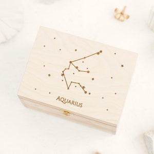 Natural wooden box with an engraving of Aquarius constellation sign, small stars and the word Aquarius in capital letter. The Zodiac sign can be selected in the personalization part. The box is presented in white background.