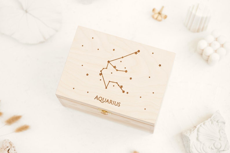 Natural wooden box with an engraving of Aquarius constellation sign, small stars and the word Aquarius in capital letter. The Zodiac sign can be selected in the personalization part. The box is presented in white background.