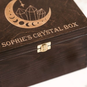 The picture shows dark brown wooden box with metal clasp. The box contains an engraving Sophie's crystal box which can be personalized.