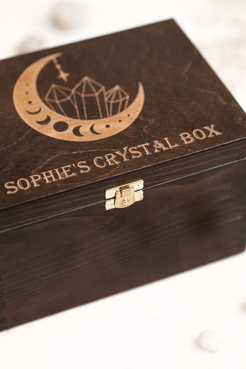 The picture shows dark brown wooden box with metal clasp. The box contains an engraving Sophie's crystal box which can be personalized.