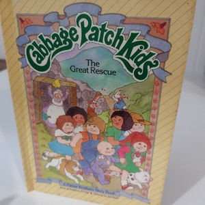 May include: A yellow, green, and blue book titled "Cabbage Patch Kids" with the words "The Great Rescue" on the cover. The cover features an illustration of a group of Cabbage Patch Kids dolls and their pets.