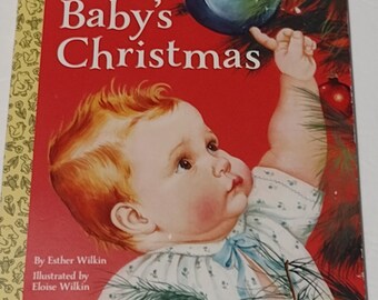 May include: A vintage children's book cover with a red background. The title "Baby's Christmas" is in large, white letters. A baby is reaching up towards a blue Christmas ornament on a Christmas tree. The book is by Esther Wilkin and illustrated by Eloise Wilkin.