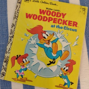 May include: A yellow Little Golden Book featuring Woody Woodpecker at the Circus. The cover shows Woody Woodpecker in a blue jumpsuit, with two other woodpeckers in pink and blue jumpsuits.