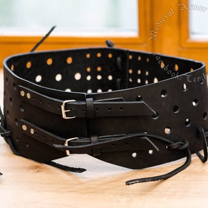 May include: Black leather belt with a perforated design and two adjustable buckles. The belt has a decorative lacing detail.