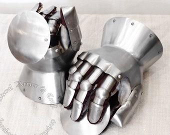 May include: A pair of silver medieval gauntlets with articulated fingers and a rounded cuff. The gauntlets are made of metal and have a polished finish.