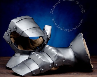 May include: A pair of medieval gauntlets made of steel, with a riveted design. The gauntlets are in a worn, aged finish, and have a textured surface. The gauntlets are lying on a wooden surface.