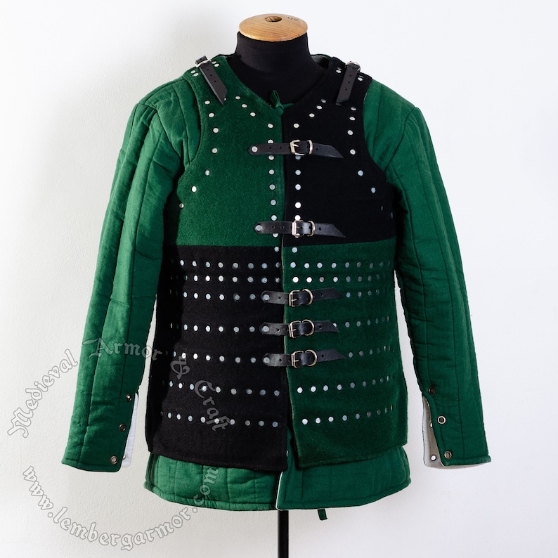 May include: A green and black padded armor vest with leather straps and buckles. The vest has a quilted design and is decorated with metal rivets.