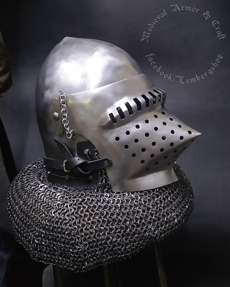 May include: A silver helmet with a visor and a chainmail coif. The helmet has a pointed top and a beak-like visor. The chainmail coif is made of small metal rings.