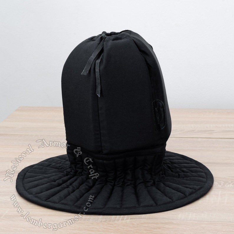 May include: Black quilted medieval coif with a drawstring closure and a wide, pleated brim. The coif is made of thick fabric and is designed to protect the head and neck.