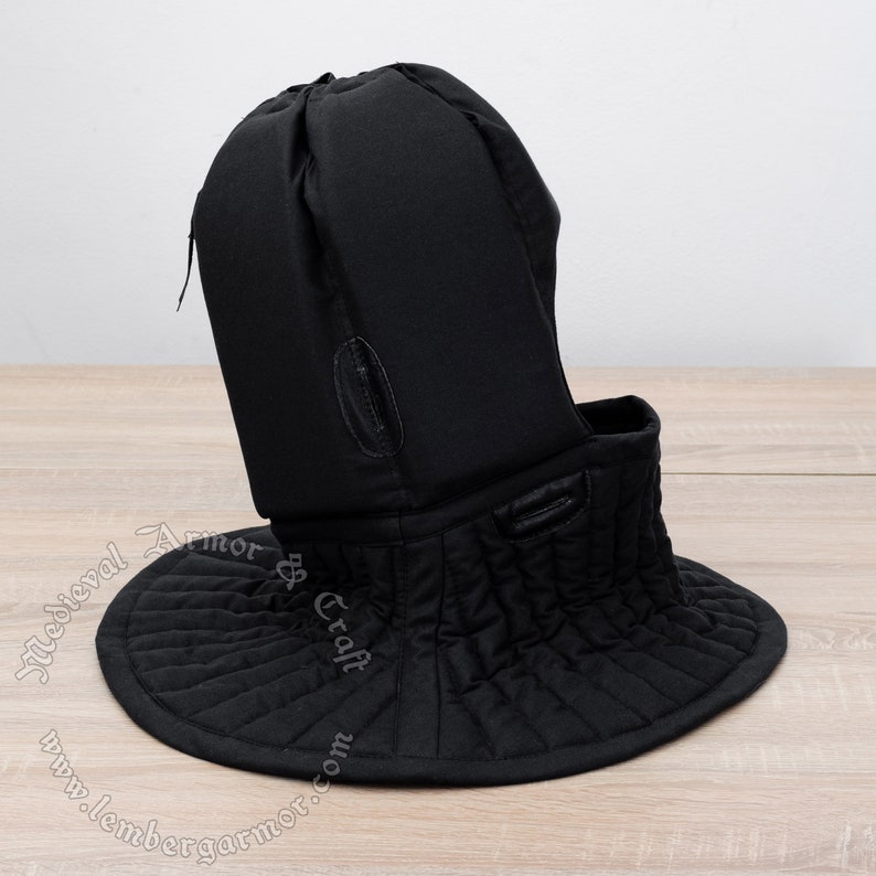 May include: Black padded medieval coif with a neck guard. The coif has a quilted neck guard and a drawstring at the top.