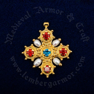 Può includere: Un ciondolo a forma di croce in oro con pietre preziose rosse e blu e perle bianche. La croce è decorata con un bordo di perline.
