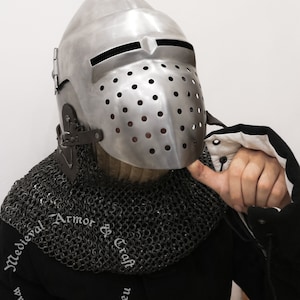 May include: A silver helmet with a face mask and a chainmail collar. The helmet has a pointed top and a visor with small holes. The chainmail collar is made of small metal rings.