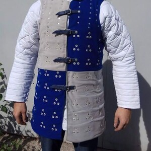 May include: A blue and grey padded vest with a quilted design and metal accents. The vest has a front closure with straps and buckles.