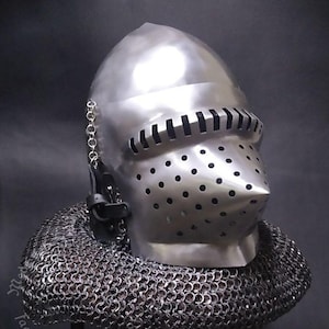 May include: A silver helmet with a face mask and a chainmail coif. The helmet has a pointed nose guard and a series of small holes in the face mask. The chainmail coif is made of small metal rings.