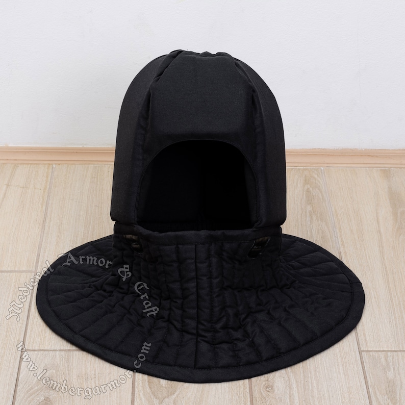 May include: Black padded medieval coif with a wide, rounded collar. The coif is made of quilted fabric and has a pointed top.