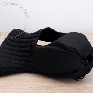May include: Black padded medieval style armor for the neck and head. The armor is made of quilted fabric and has a drawstring closure.