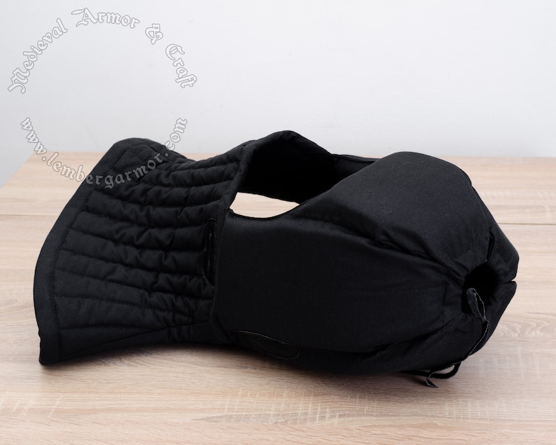 May include: Black padded medieval style armor for the neck and head. The armor is made of quilted fabric and has a drawstring closure.
