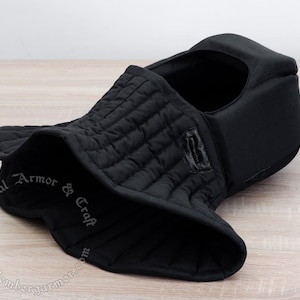 May include: Black quilted padded medieval hood with a neck guard. The hood is made of thick fabric and has a soft lining. It is designed to protect the head and neck from injury.