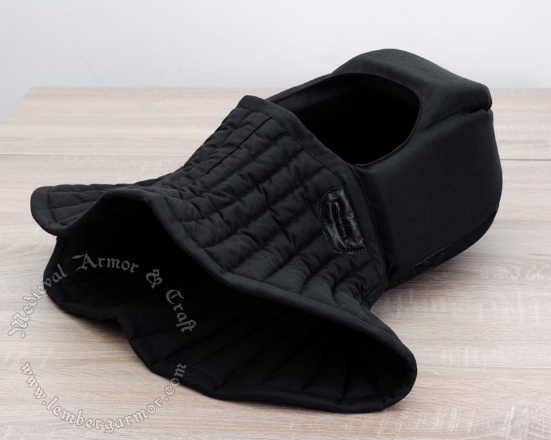 May include: Black quilted padded medieval hood with a neck guard. The hood is made of thick fabric and has a soft lining. It is designed to protect the head and neck from injury.