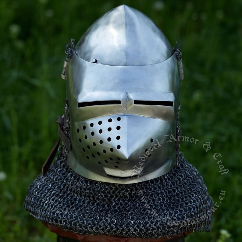 May include: A silver helmet with a face mask and a chainmail collar. The helmet has a pointed top and a visor with a small opening for the eyes. The face mask has a series of small holes for ventilation. The chainmail collar is made of interlocking metal rings.