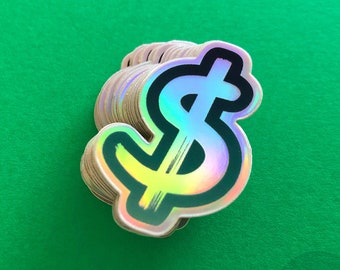 May include: A stack of iridescent holographic stickers featuring a black outline of a dollar sign. The dollar sign is filled with a rainbow of colors.