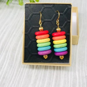May include: Rainbow coloured stacked stone earrings with gold hooks. The earrings are displayed in a small box.
