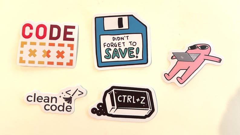 Peut inclure: Un ensemble de cinq autocollants en vinyle avec des motifs technologiques : une &eacute;tiquette rouge CODE, une disquette bleue avec le texte DIDN'T FORGET TO SAVE!, un personnage rose utilisant un ordinateur portable, une &eacute;tiquette clean code et une gomme noire CTRL+Z.
