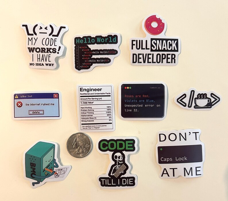 Peut inclure: Un ensemble de onze autocollants en vinyle avec des graphismes et du texte sur le th&egrave;me de la programmation, incluant des phrases comme My Code Works, Full Snack Developer et Don't Caps Lock At Me, pr&eacute;sent&eacute;s avec une pi&egrave;ce pour l'&eacute;chelle.