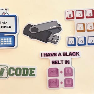 Peut inclure: Un ensemble de cinq autocollants en vinyle avec des motifs technologiques. On y voit un ordinateur avec un chat et le texte I AM DEVELOPER, une cl&eacute; USB, des touches de clavier BORN TO CODE, une ic&ocirc;ne de souris avec le mot CODE et un raccourci clavier.