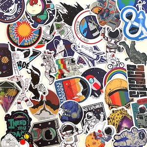 May include: A collection of assorted space-themed stickers featuring various illustrations of astronauts, planets, rockets, and cosmic imagery. The stickers include text such as "SPACE EXPLORER," "EVERYDAY ASTRONAUT," "TIME & SPACE," and "I NEED my SPACE" in diverse colors.
