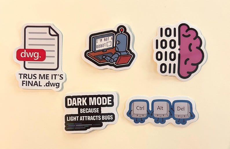 Peut inclure: Cinq autocollants en vinyle avec des motifs technologiques : une ic&ocirc;ne de document avec le texte 'TRUS ME IT'S FINAL .dwg', un robot devant un ordinateur avec 'I'M NOT A ROBOT', un cerveau avec du code binaire, 'DARK MODE BECAUSE LIGHT ATTRACTS BUGS' et les touches Ctrl Alt Del.