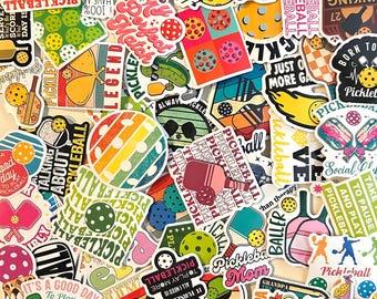 May include: A collection of colorful vinyl stickers featuring various pickleball-themed designs, including paddles, balls, and text such as Pickleball, Dinking Problem, and Born to Pickle, arranged in a dense, overlapping pile.