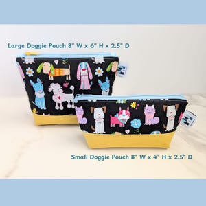 May include: Two zippered pouches with a black background and a colorful pattern of dogs and flowers. The larger pouch is 8 inches wide by 6 inches high by 2.5 inches deep. The smaller pouch is 8 inches wide by 4 inches high by 2.5 inches deep. Both pouches have a yellow bottom and a light blue zipper.